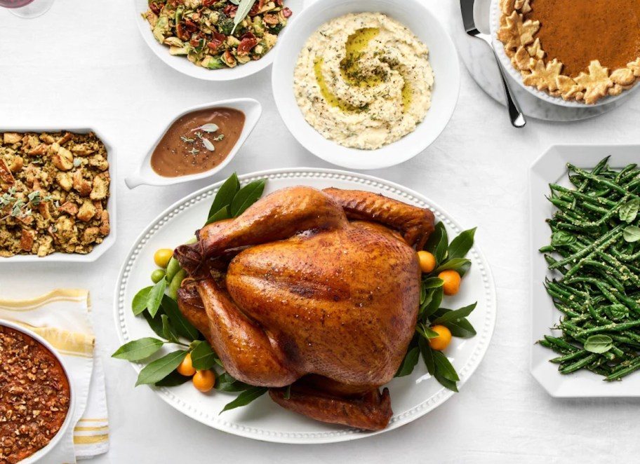 whole cooked turkey and side dishes on white table