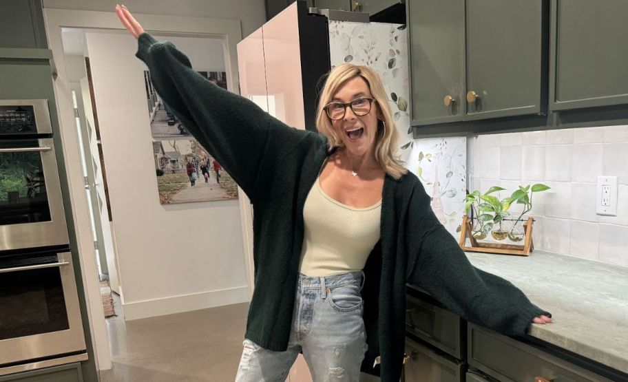 a woman in a green sweater standing in a kitchen