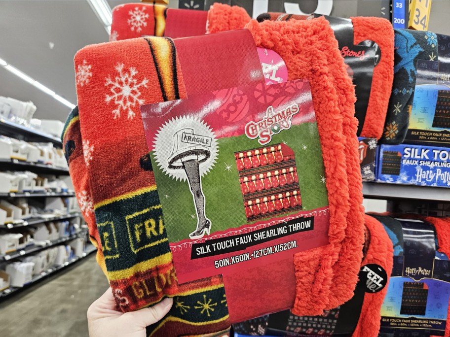 hand holding up red christmas story leg lamp throw blanket in store