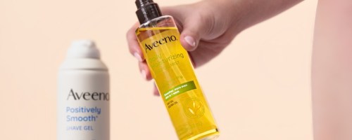 woman holding aveeno daily moisturizing oil mist bottle