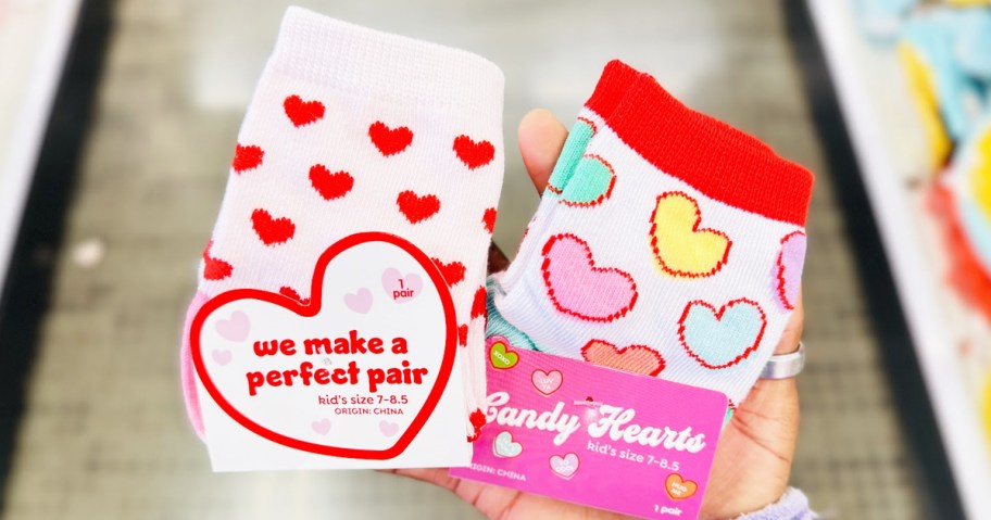 hand holding up two pairs of kids heart print socks