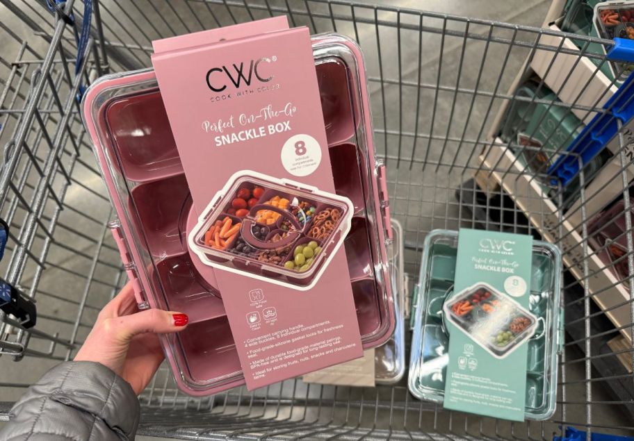 a womans hand holding a pink colored snackle box