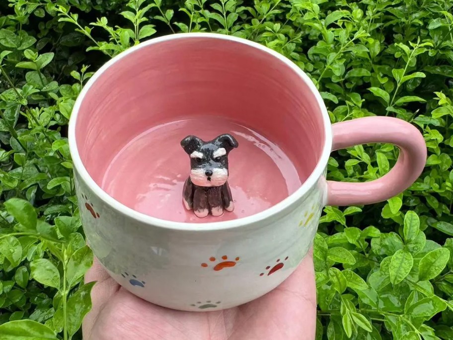 hand holding a pink mug with a dog on the inside