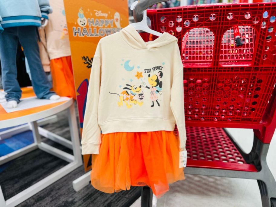 A tan sweatshirt attached to an orange tule skit hanging on a red Target cart