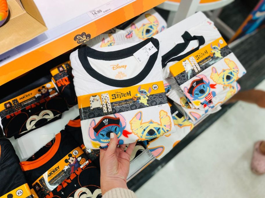 A person holding a pair of white pajamas in a store