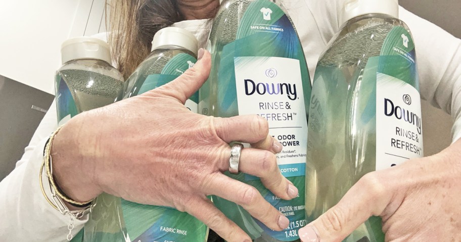 woman holding 4 bottles of Downy Rinse & Refresh