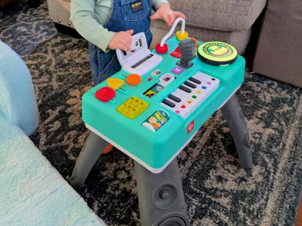 little toddler playing with Fisher Price DJ table