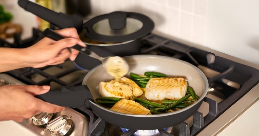 a person cooking food in a saute pan on a stove