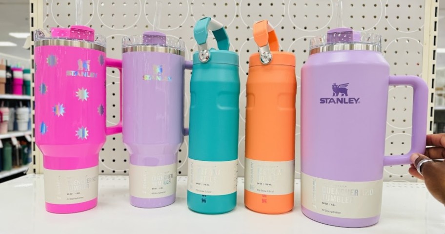 Stanley Tumblers and water bottles in bright pastel pinks, lavenders, teal, and orange on a Target store shelf