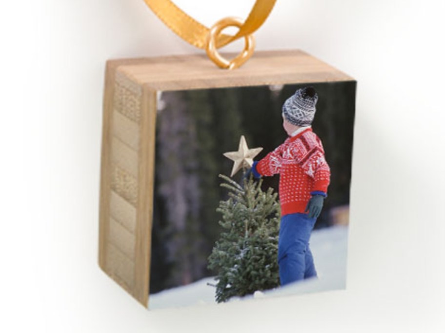 a bamboo wood photo ornament with a picture of a little boy in the snow putting a star on a small tree