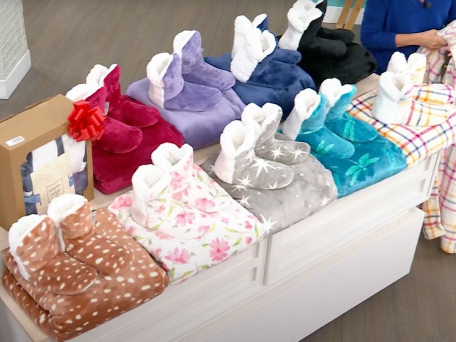 A Table with several sets of slippers and matching throw blankets