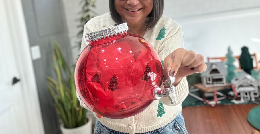 A woman holding a Holiday Time Ornament Beverage Dispenser in red