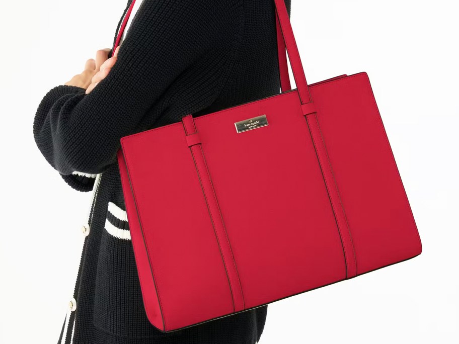 woman in a black sweater with a red tote bag