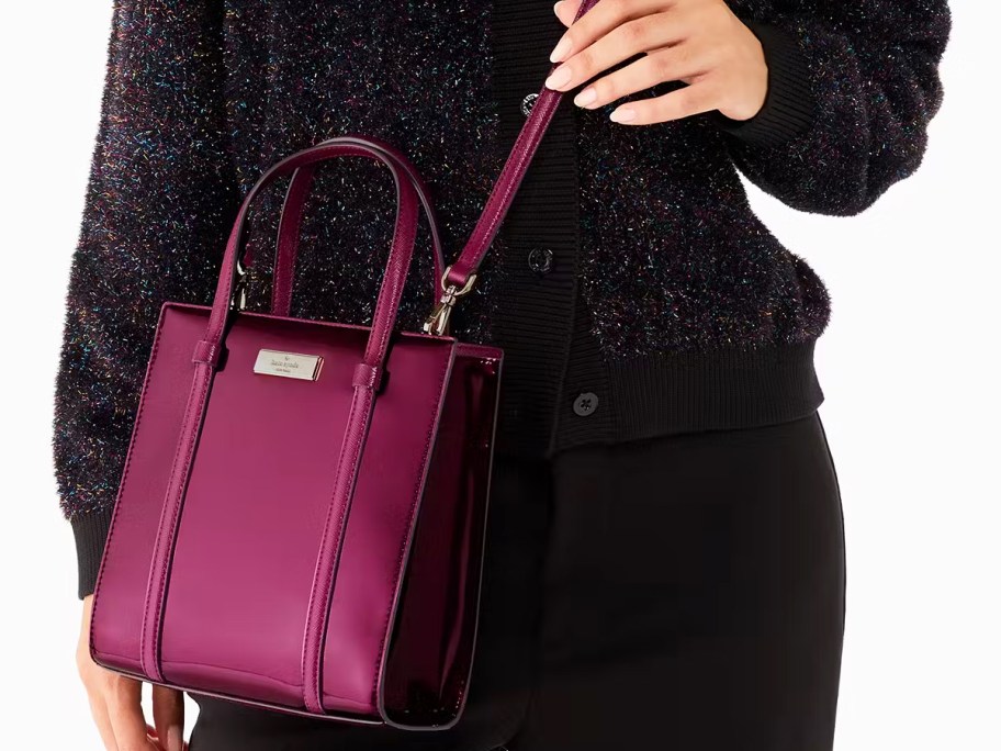 woman in a black outfit with a maroon mini tote bag