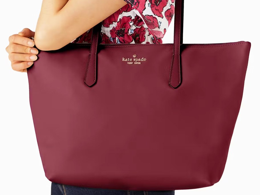 woman in a floral top with a maroon tote bag