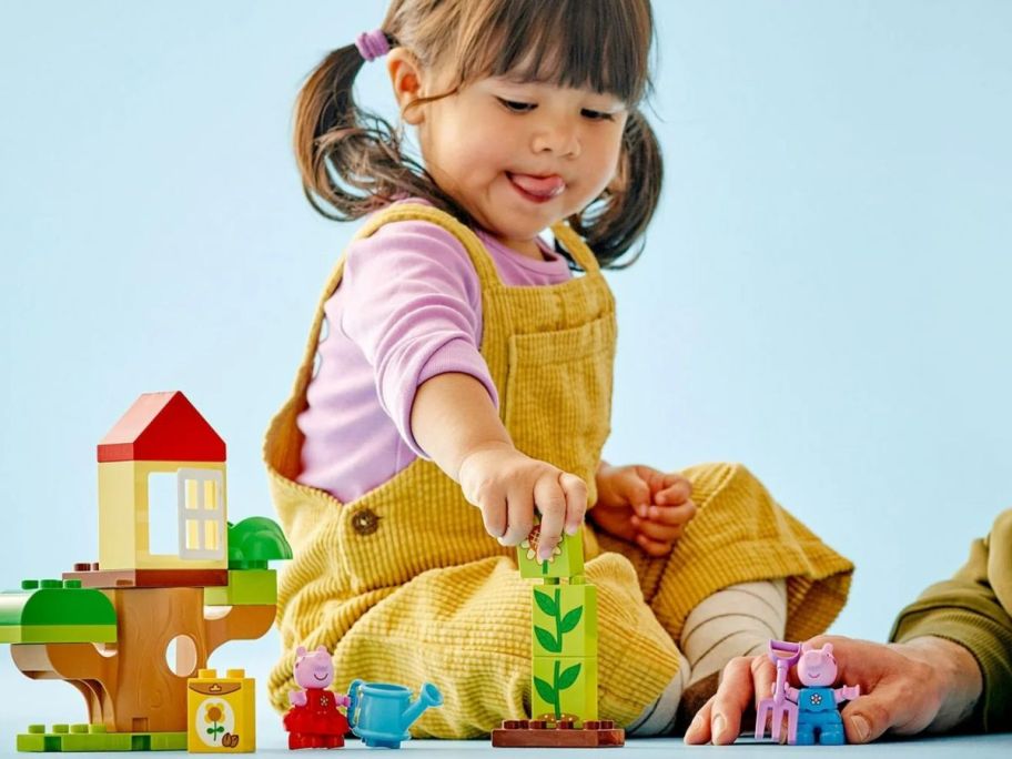 Little girl playing with a LEGO DUPLO Peppa Pig Garden and Tree House