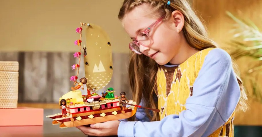 girl holding the LEGO Disney Moana's Adventure Canoe set