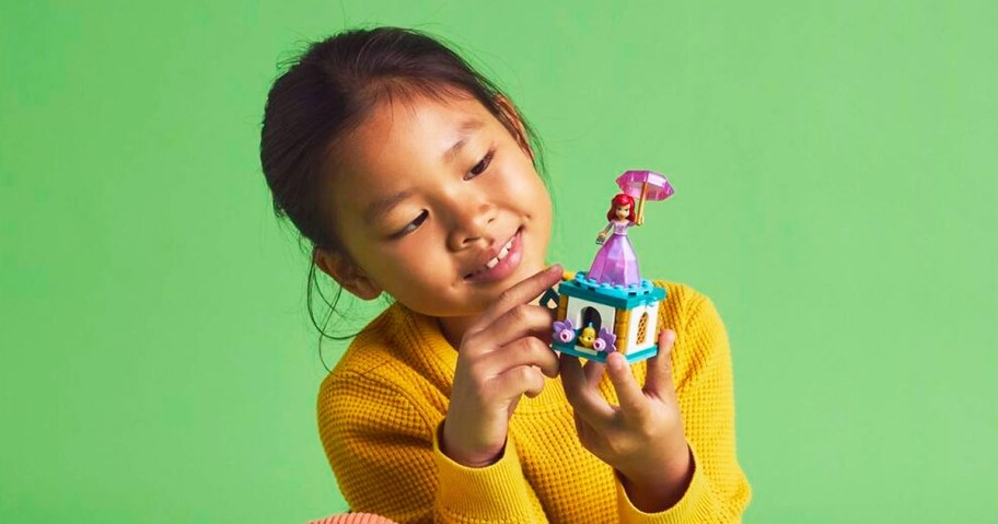 girl in yellow sweater holding the LEGO Disney Princess Twirling Ariel set