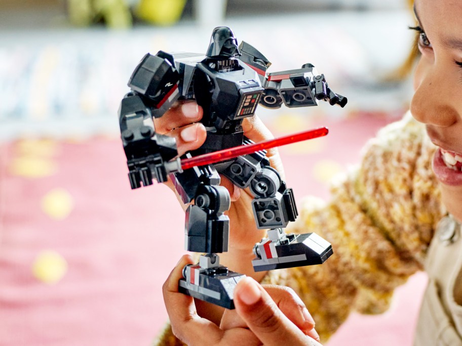 girl holding LEGO Star Wars Darth Vader Mech Action Figure