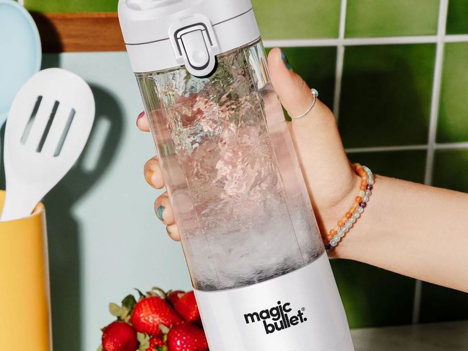 A person holding a magic bullet filled with water