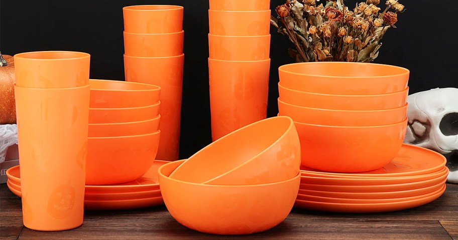 stacks of orange plastic cups, bowls, and plates with pumpkin print