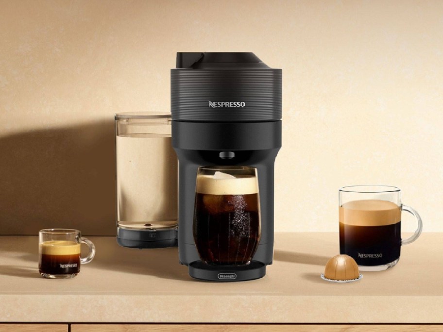 Nespresso machine with iced coffee on the side and with a pod