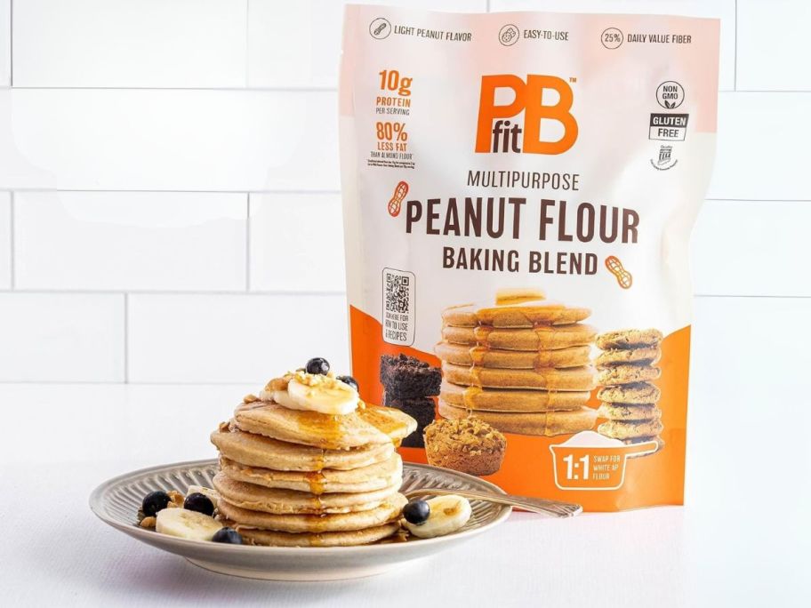 PBfit Peanut Flour Baking Blend 24oz bag on table next to stack of pancakes