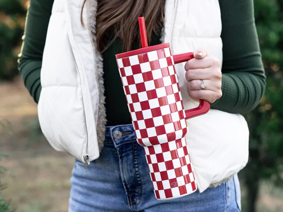 woman holding a red and white checkered print tumbler