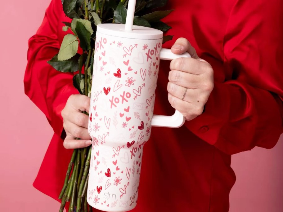 woman in red shirt holding up a love doodle print tumbler