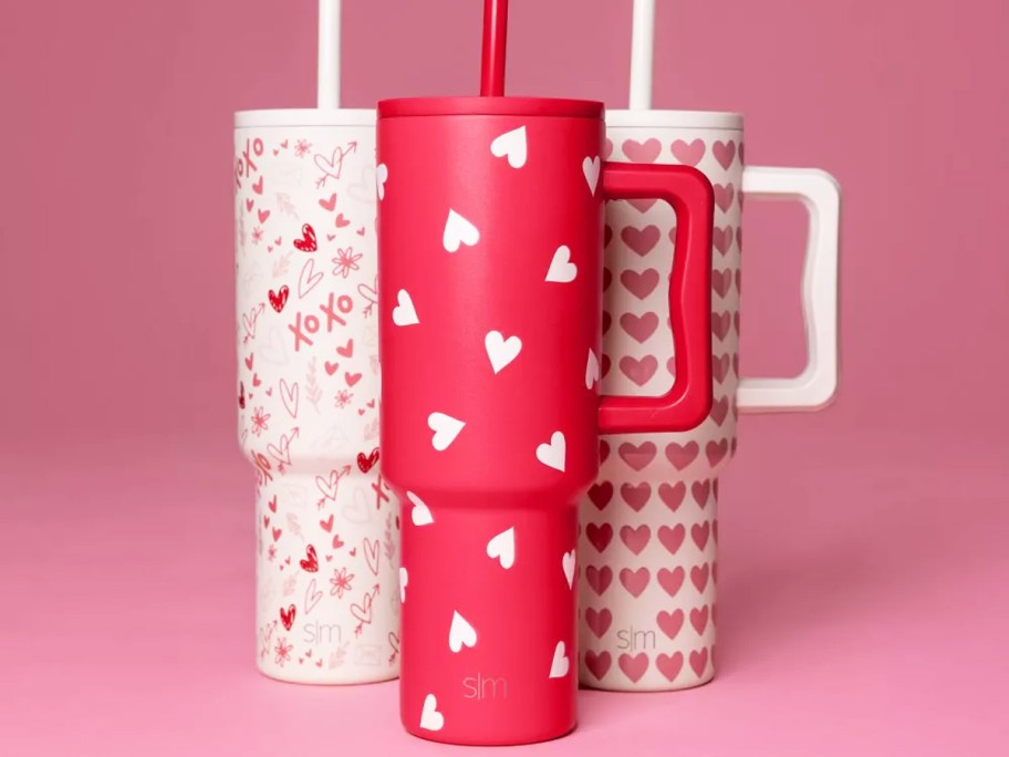 three valentines day print tumblers with a pink background