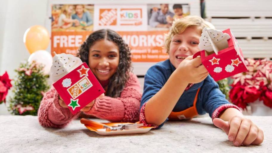 Two kids at Home Depot workshop, holding up hot cocoa craft