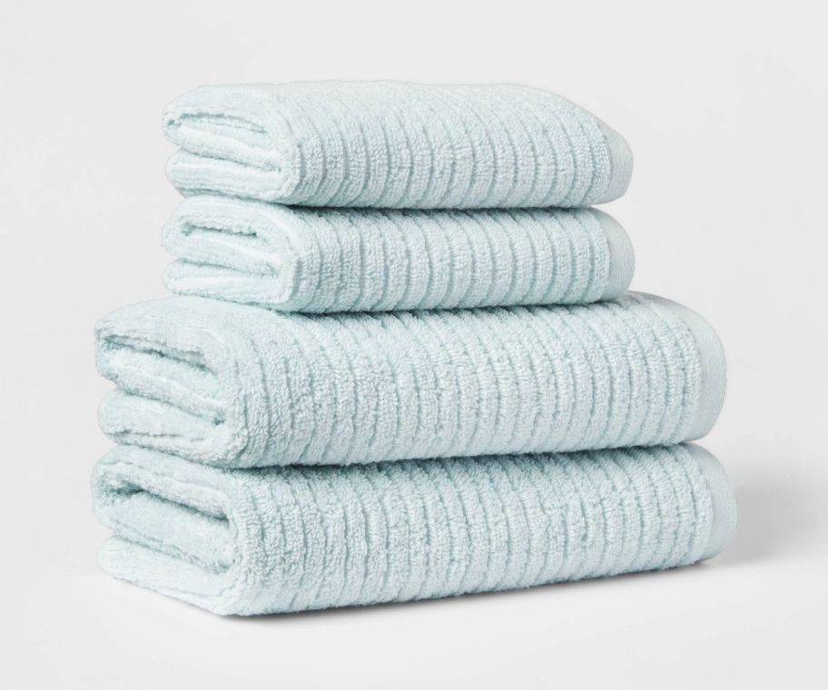 two aqua blue towels and two matching washcloths in a stack