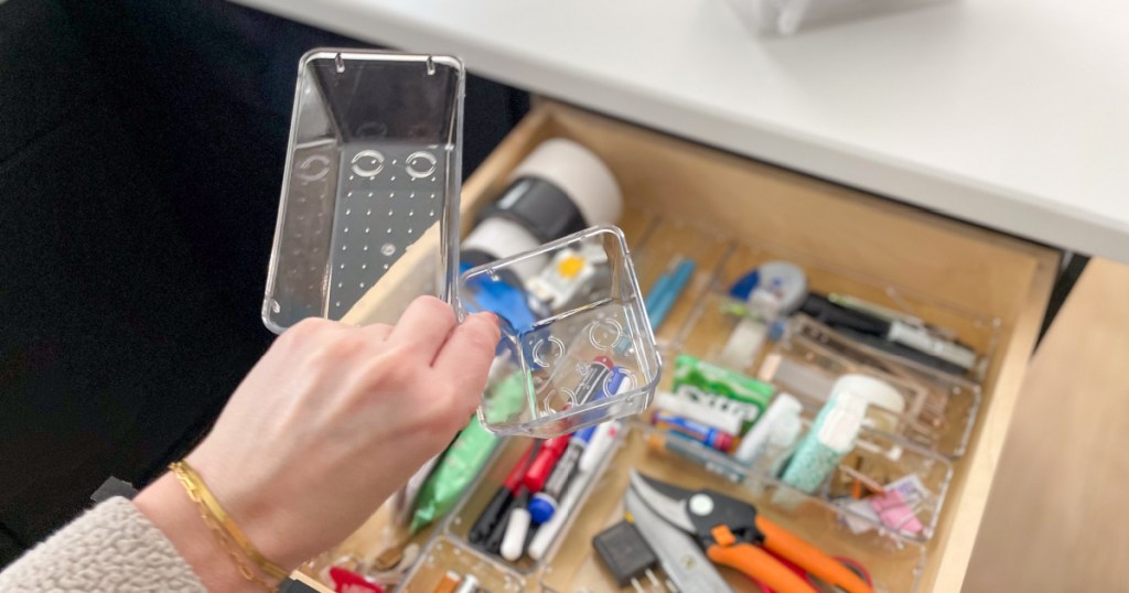 person holding clear plastic containers above drawer