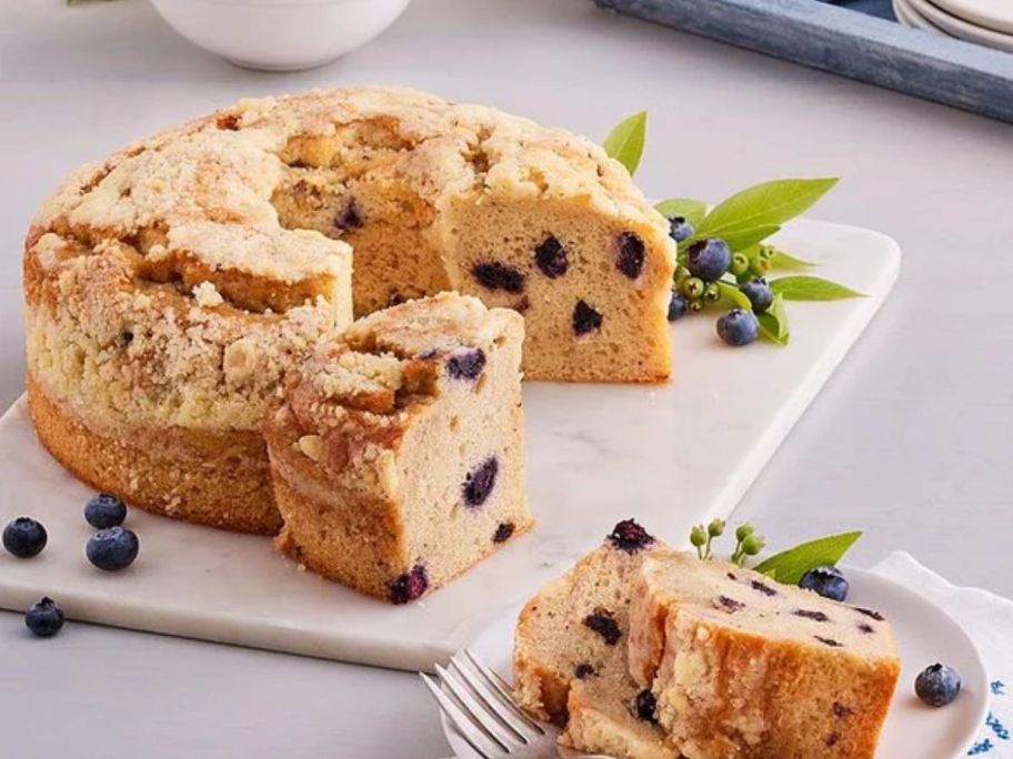 A blueberry coffee cake on a cutting board with mint