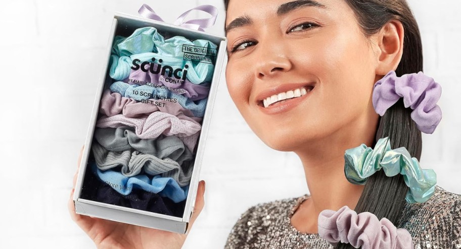 Woman holding box of scrunches in her hairs with some on her ahir