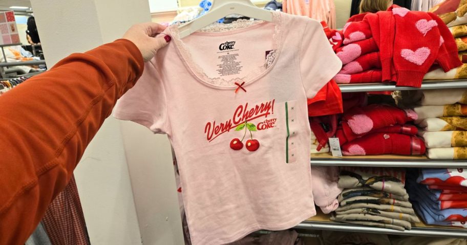 Women's Very Cherry Coke Cap Sleeve Graphic Baby T-Shirt in hand in store