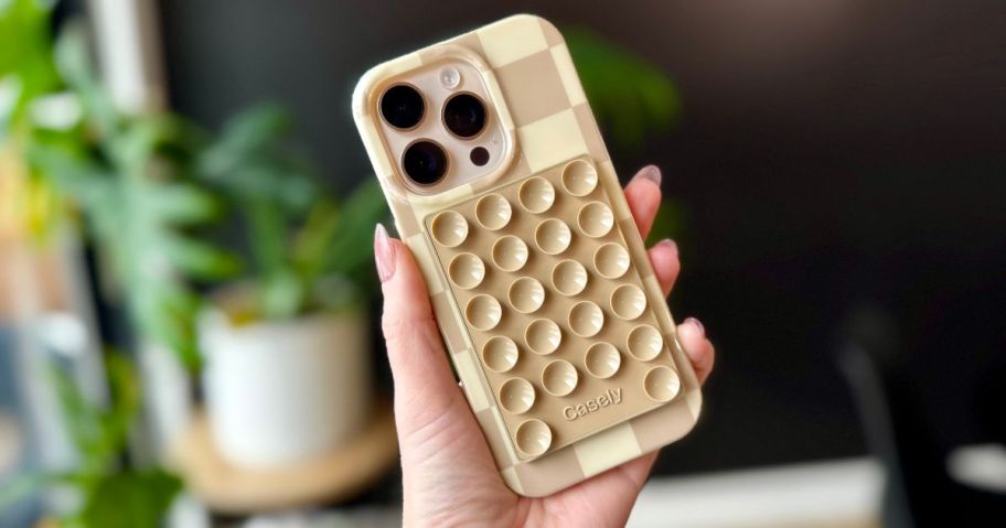beige square shaped designed phone case with Casely Grippy Silicone Suction Phone Mount on it in hand
