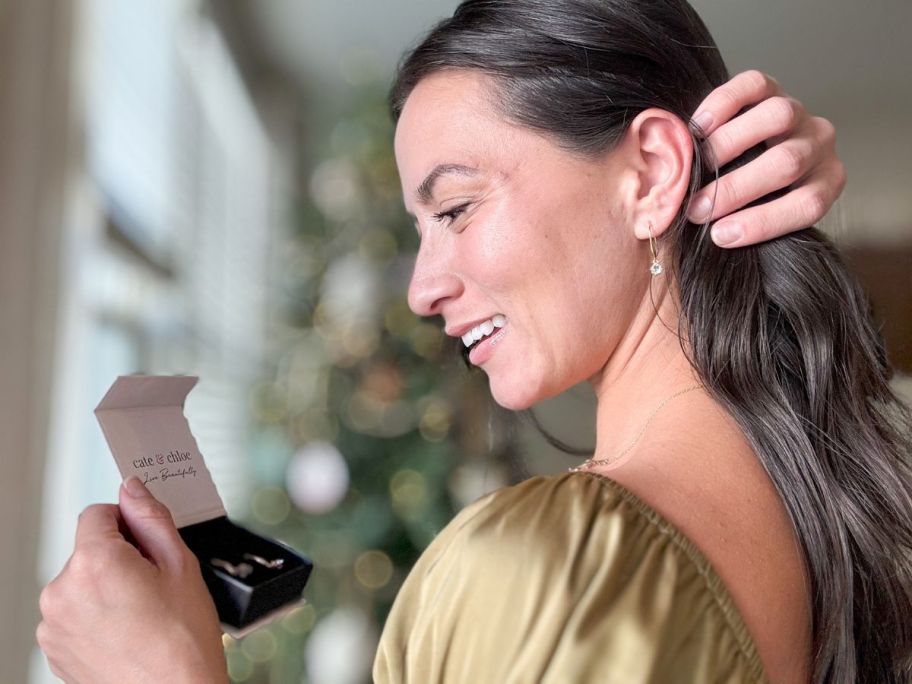 woman pulling hair back revealing drop earrings