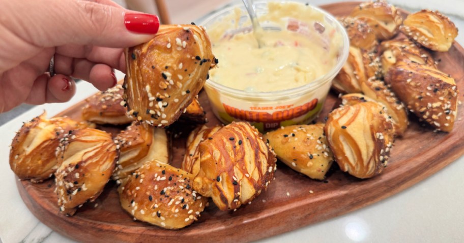 holding a pretzel bite on a platter 