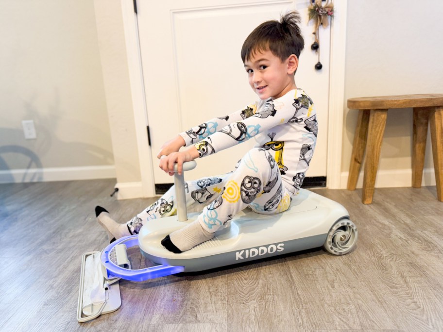 little boy on pajamas riding on a mopping cart