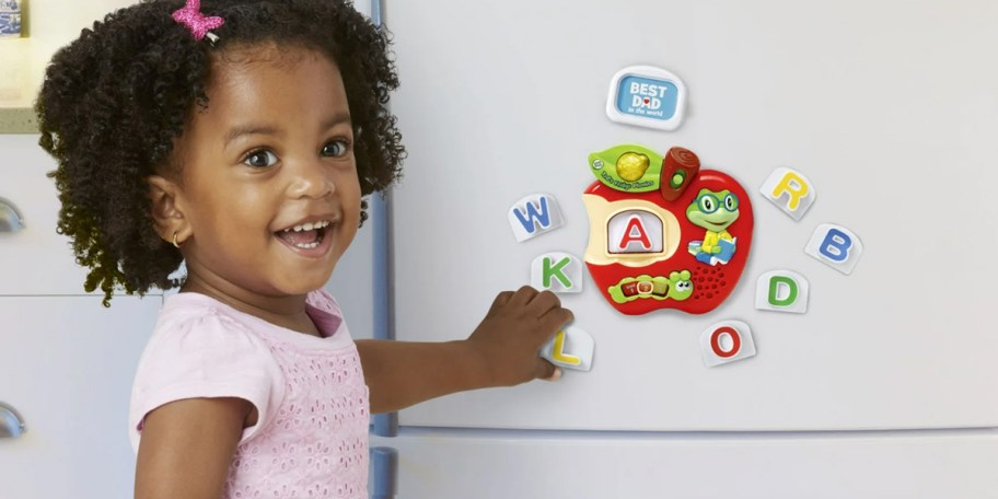 girl putting frige phonics on fridge