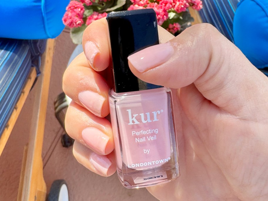 hand holding pink kur nail polish
