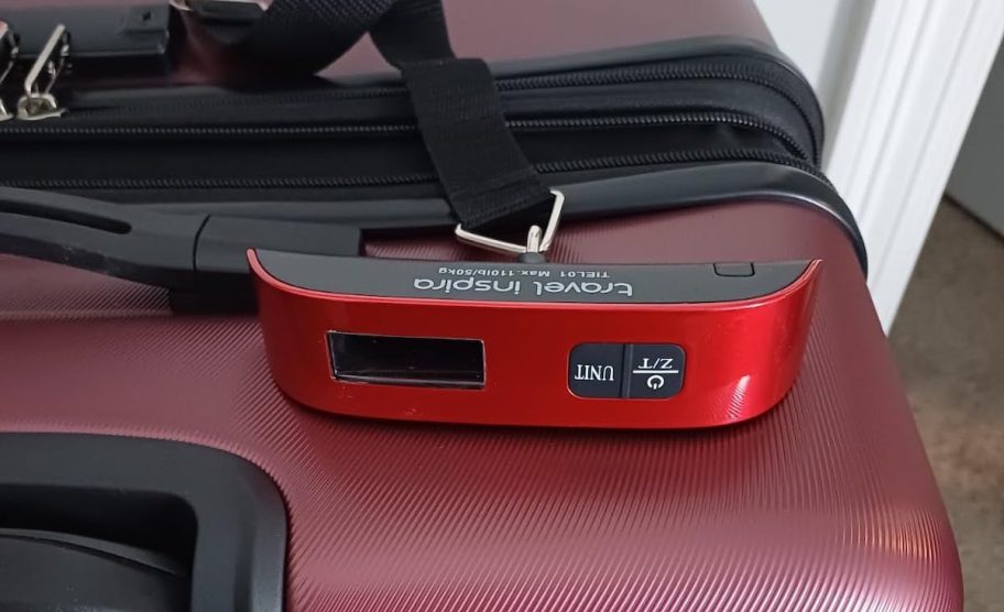 red luggage scale on burgundy colored suitcase