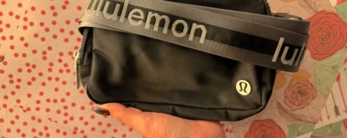 woman holding up black lululemon Wordmark Belt Bag