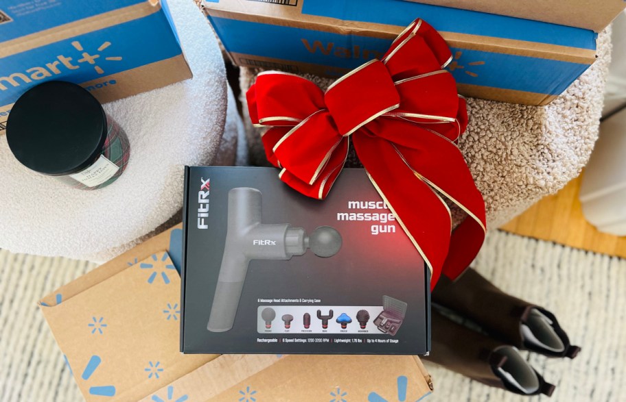 massage gun in the box with a bow resting on top, near walmart boxes