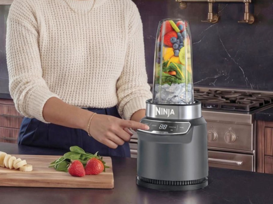woman starting blender full of fruit