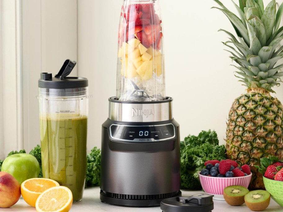 ninja blender with cup full of fruit on table with fruit