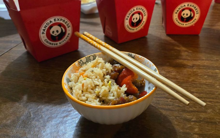 a bowl of food with chopsticks shown with red panda express food containers