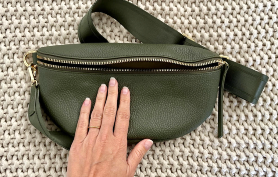 hand on top of green leather sling bag