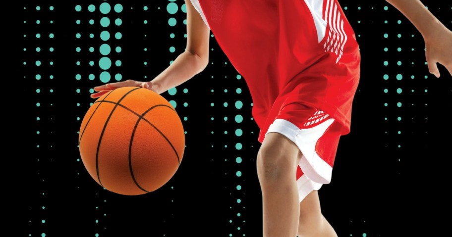 boy in a red and white uniform dribbling a foam basketball